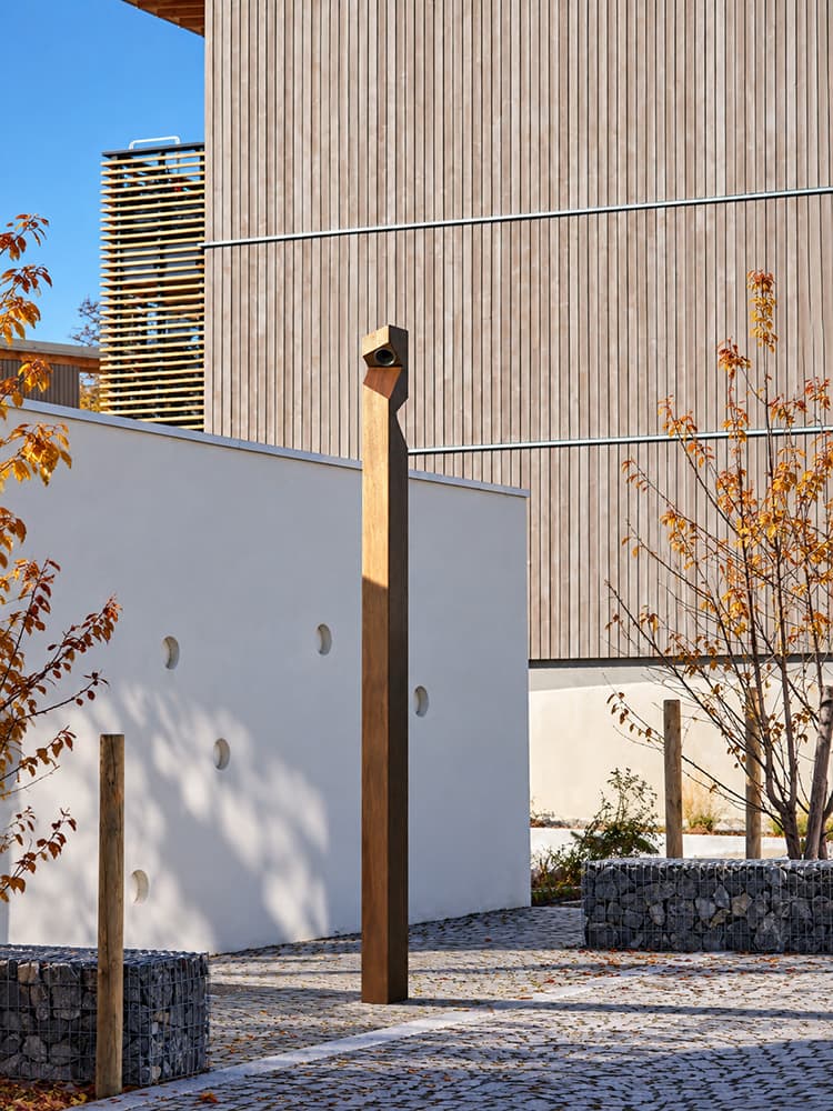 Eine Leuchtsäule aus Holz in modernem Design, aufgestellt in einer städtischen Umgebung.